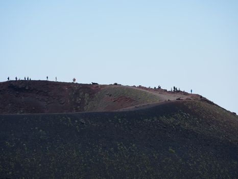 Hikers exploring the rugged landscape of Mount Etna, Sicily, under a clear sky.