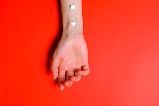 Conceptual image of pills on an arm against a bold red background for medical themes.