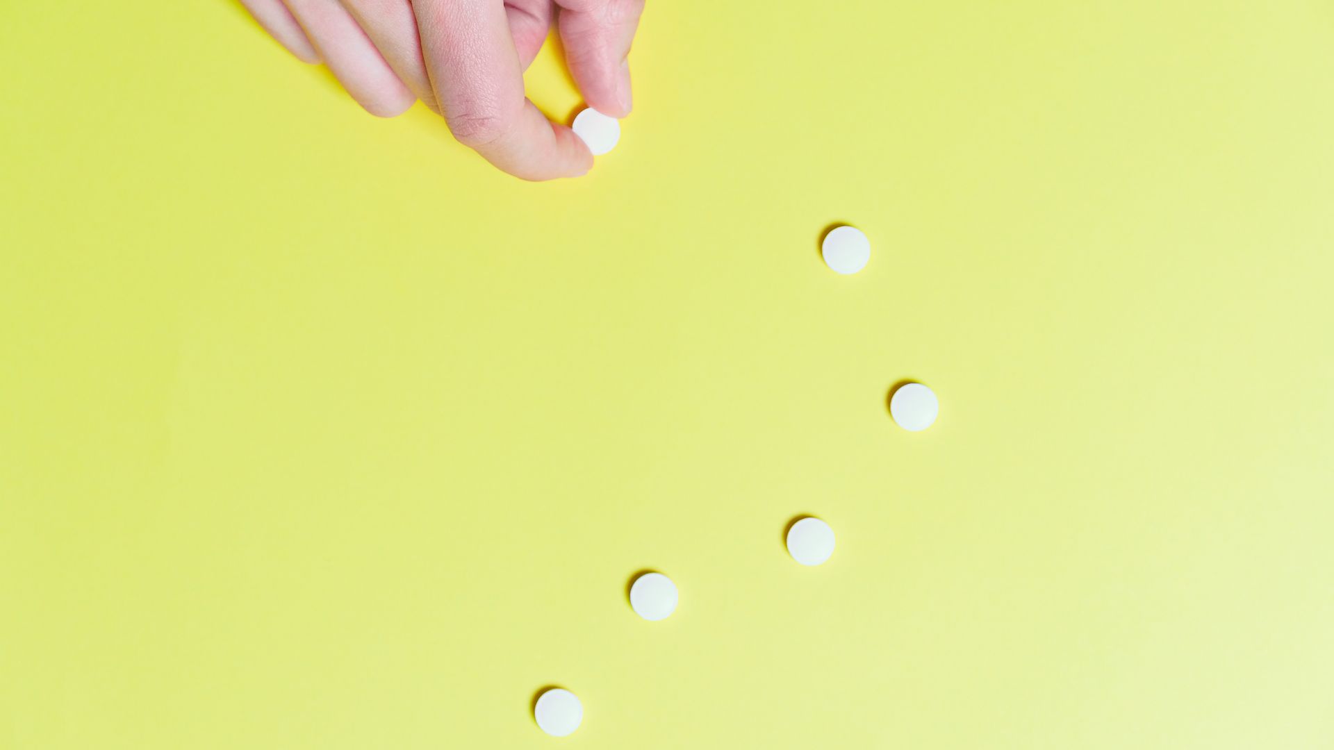 Modafinil FDA Approved Uses: Unlocking the Mystery Hand holding white pills on a bright yellow background, displaying medical and pharmaceutical concepts.