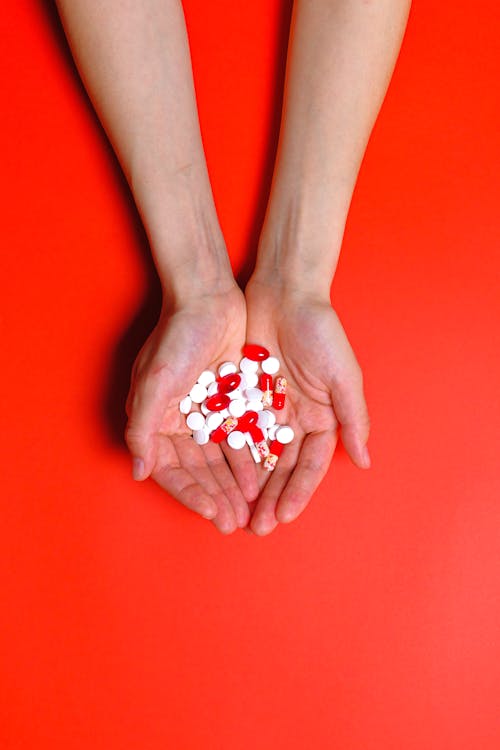 Person Holding White and Red Medical Pills and Capsules