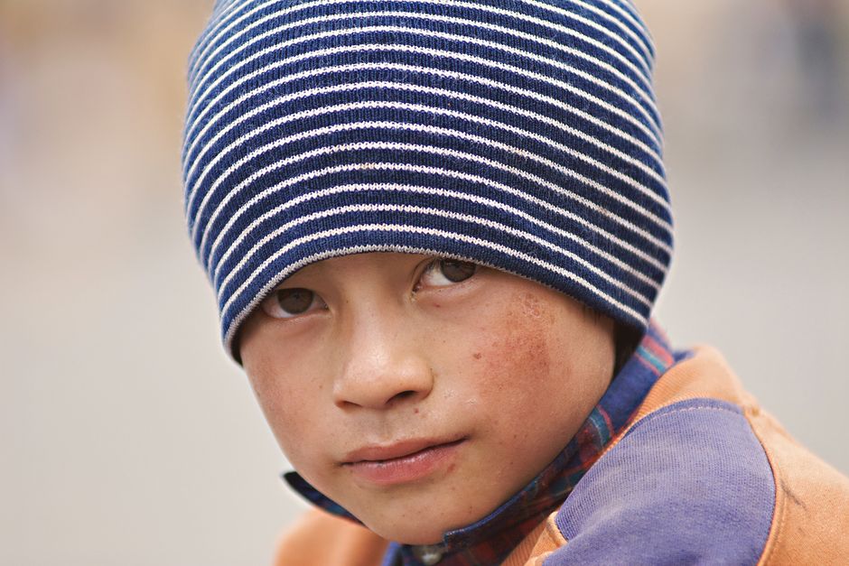 Close-up portrait of a child wearing a striped beanie in Quito, capturing an emotional gaze.