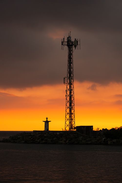 Free Stunning sunset view of Yalova harbor with a lighthouse and communication tower silhouette. Stock Photo