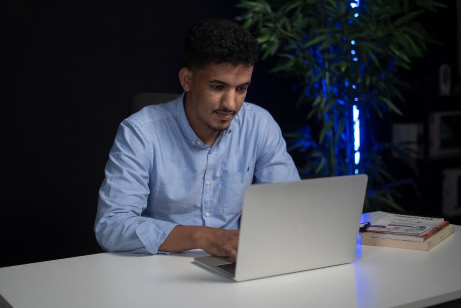 Focused SaaS founder working on a laptop in a dimly lit office, preparing the launch