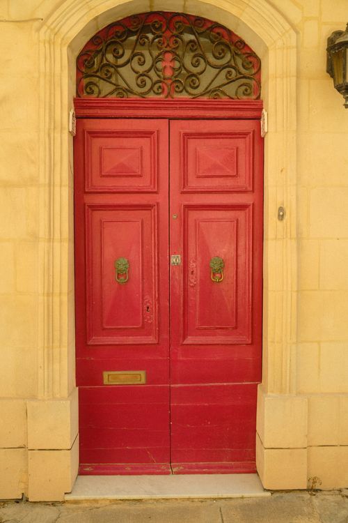 Free Vibrant red wooden door set in stone, showcasing Malta's historic architecture. Stock Photo