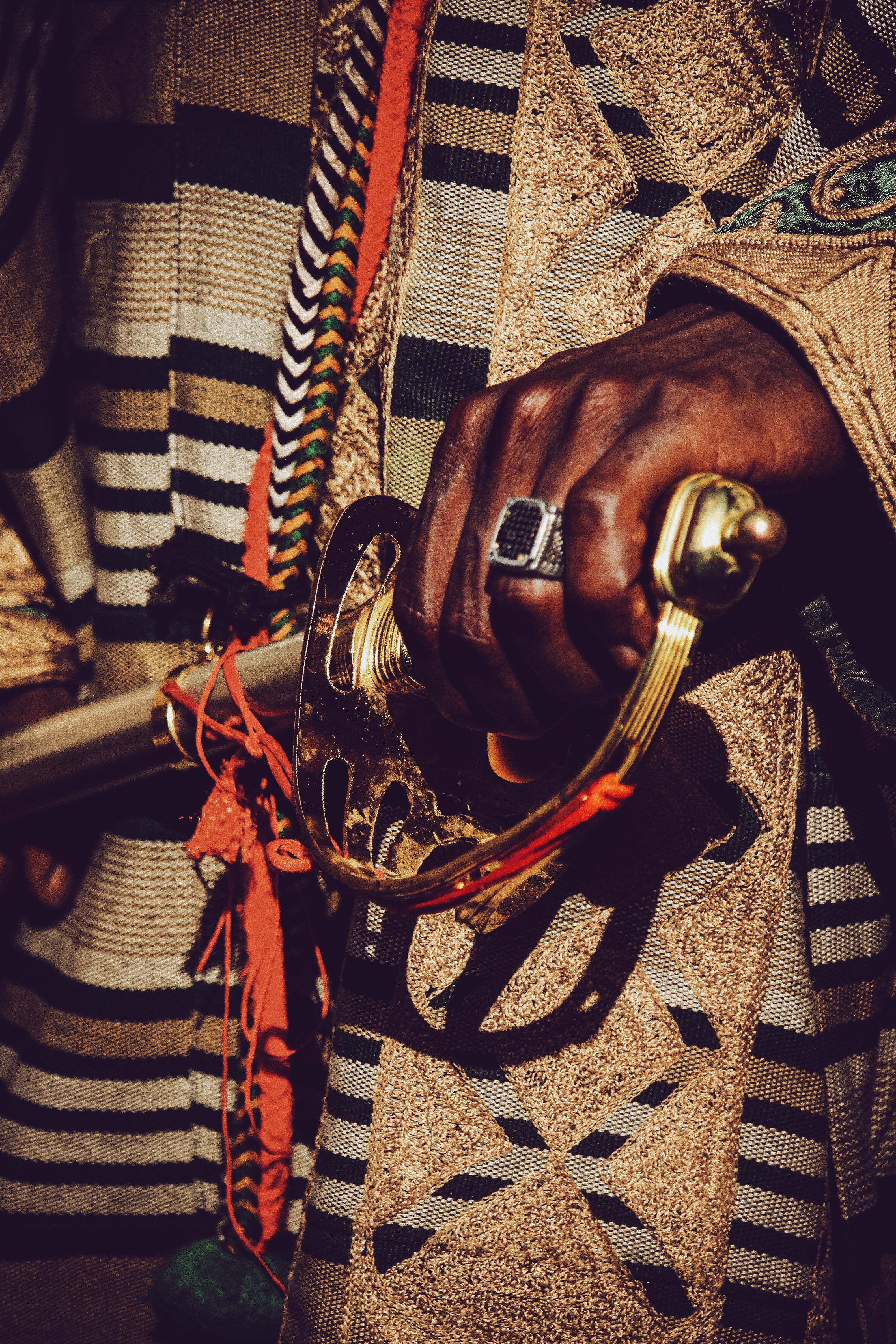 Close-up of a decorative African sword held by a hand in cultural attire.