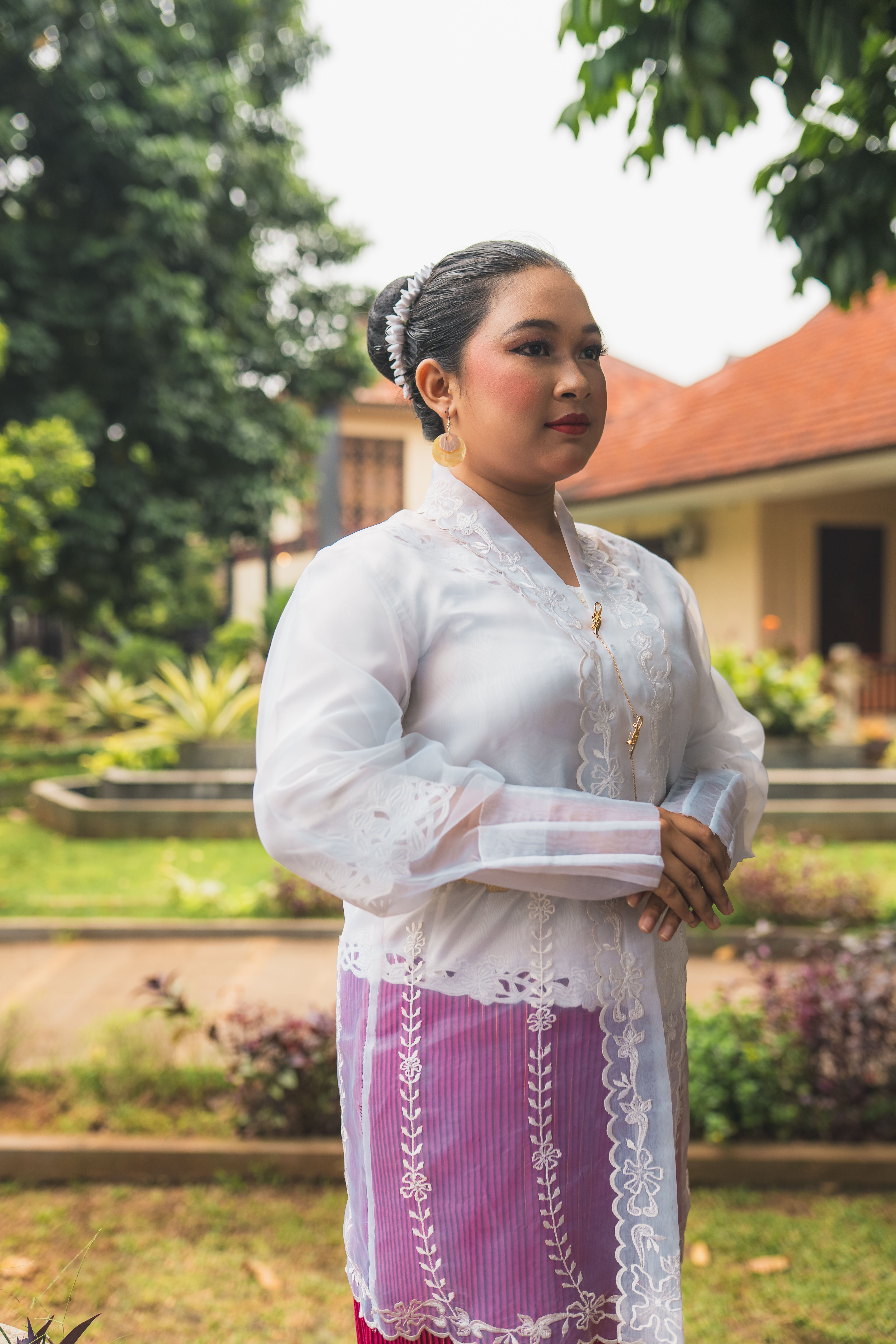 A woman in traditional Indonesian kebaya attire poses outdoors in Jakarta, showcasing cultural heritage.