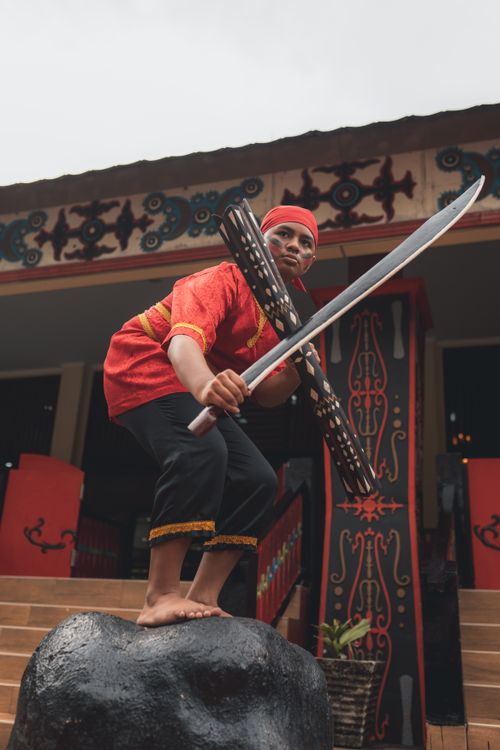 Free Indonesian warrior poised with sword and shield in traditional attire in Jakarta. Stock Photo