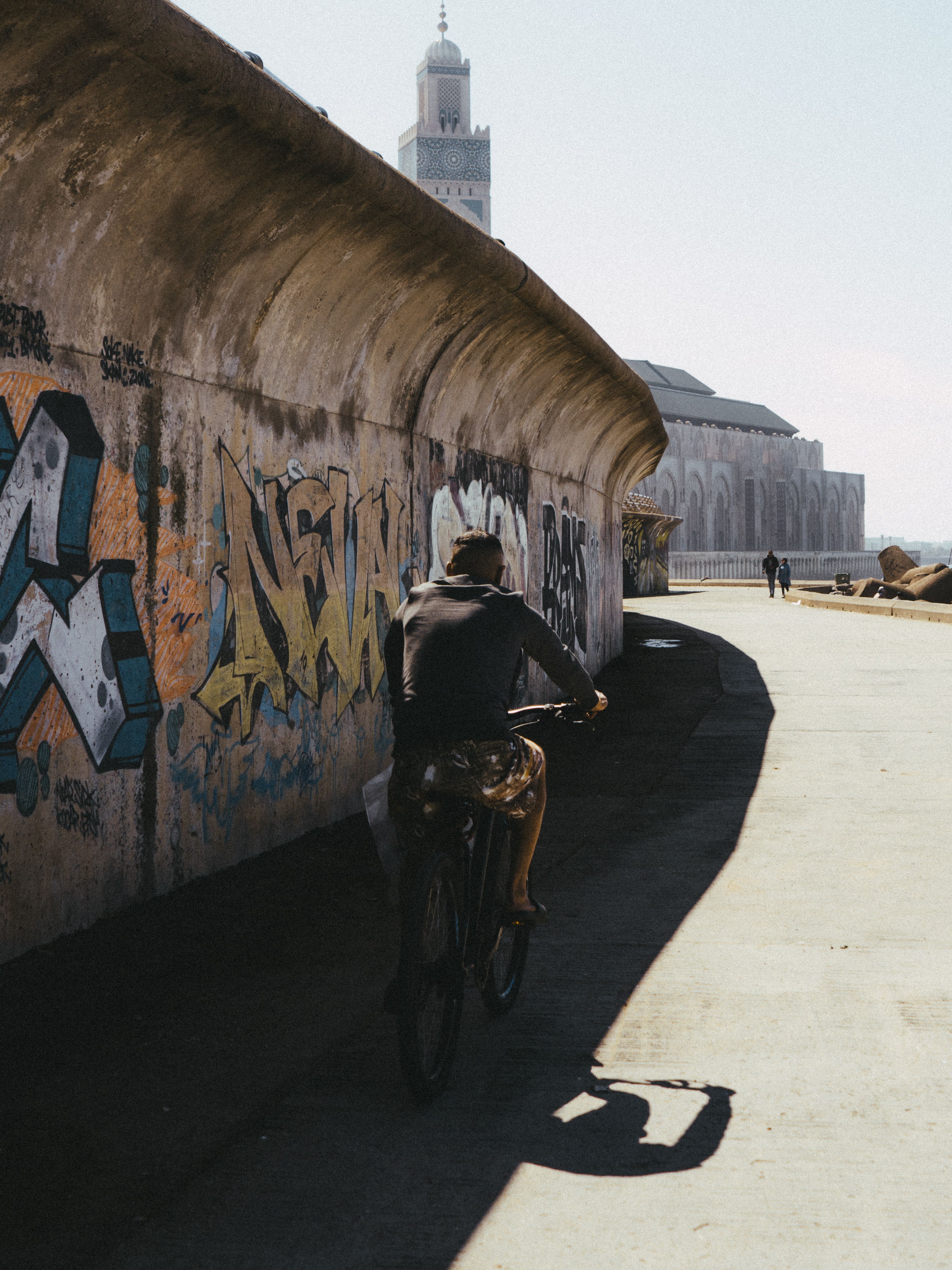 A cyclist rides past graffiti towards the Hassan II Mosque in Casablanca, Morocco.