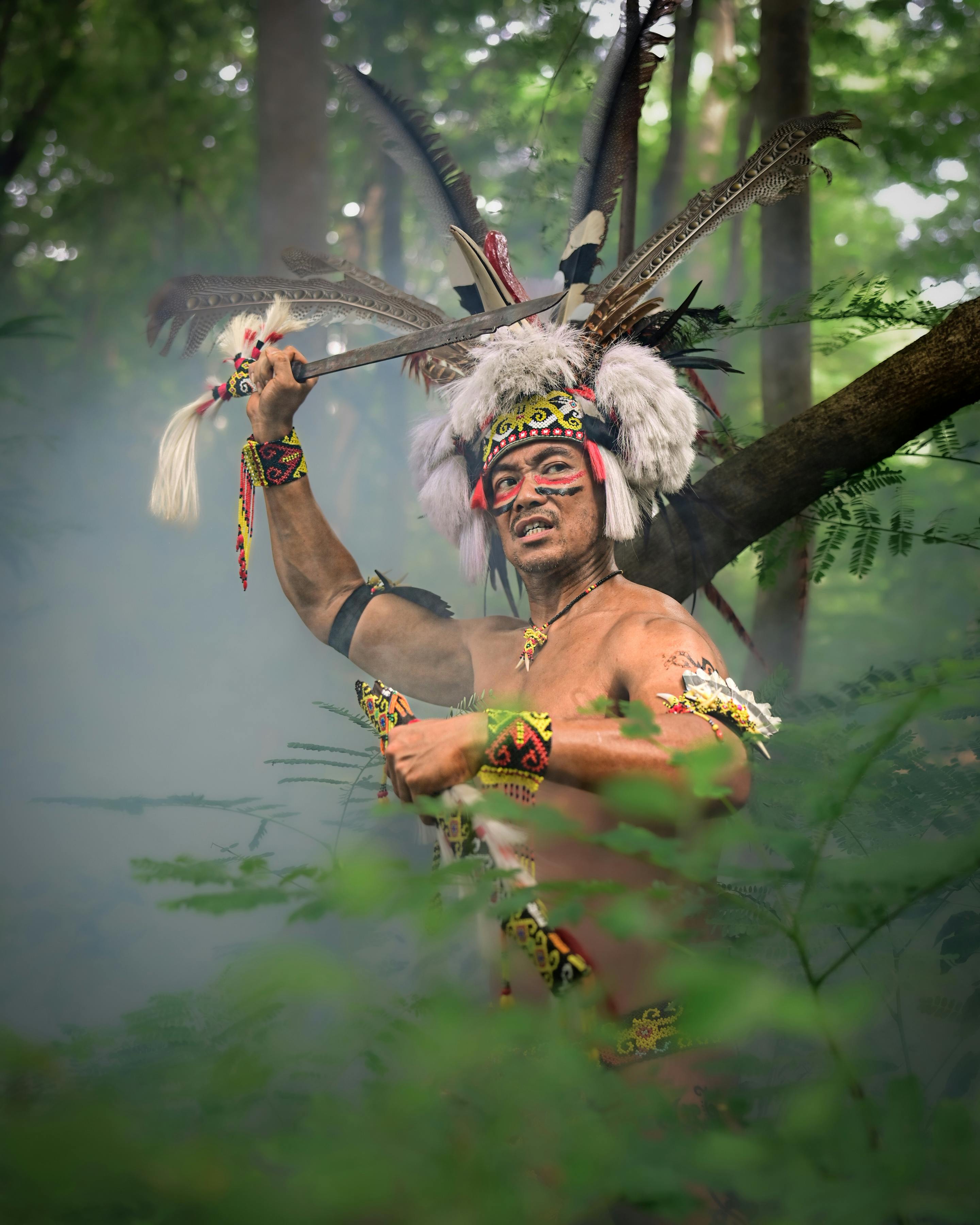 A Dayak warrior in traditional attire performing a ritual in the lush forests of West Kalimantan.