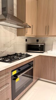 Contemporary kitchen featuring a gas stove, microwave, and wood cabinetry.