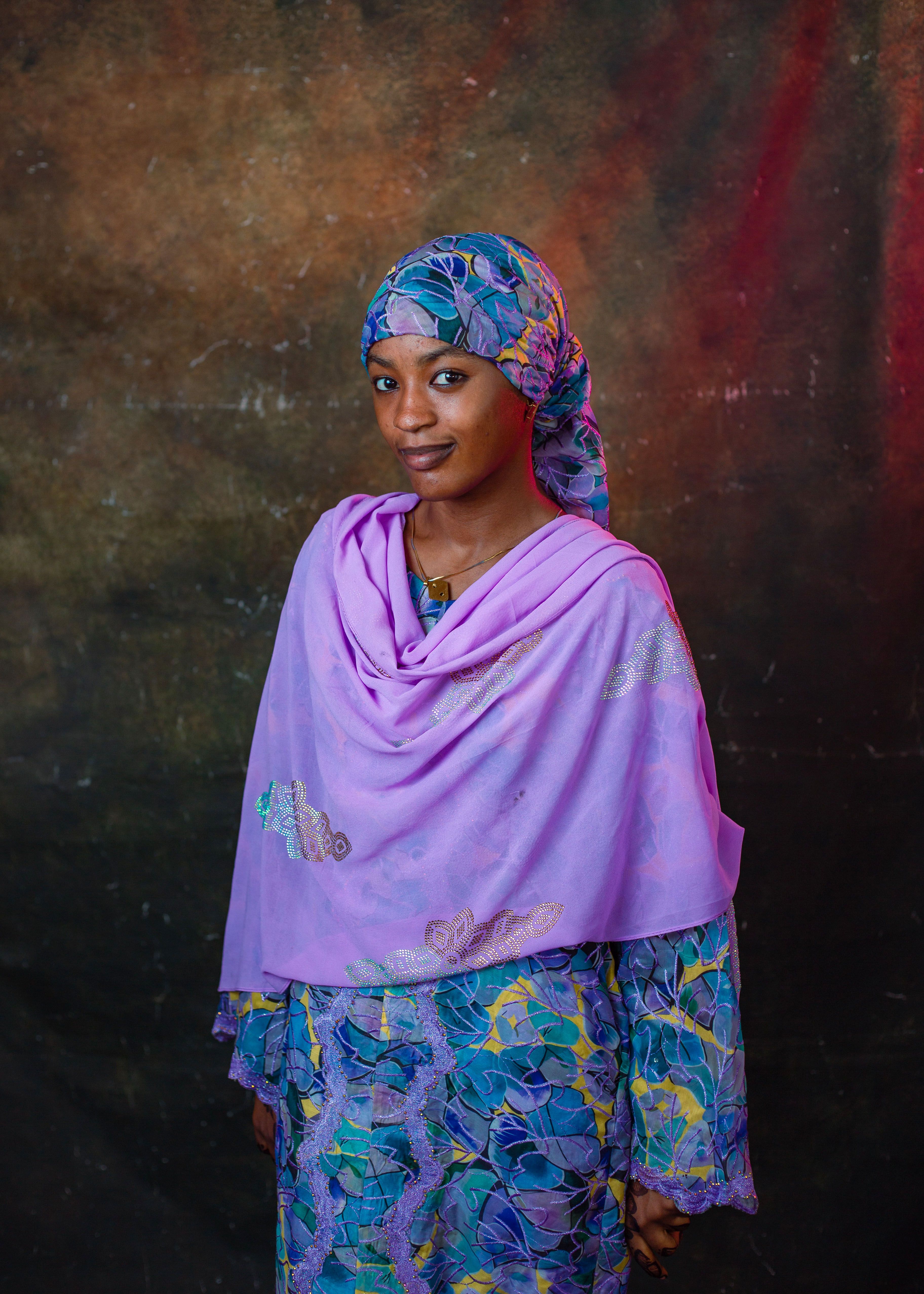 A beautiful portrait of an African woman wearing colorful traditional attire against a textured background.