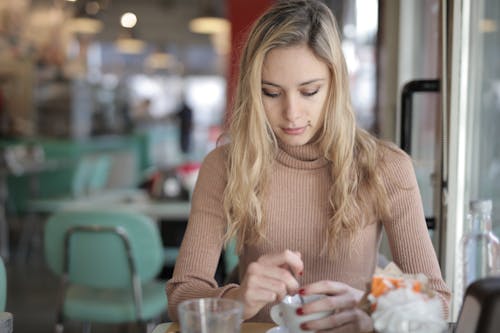 Femme En Col Roulé Marron Tenant Une Tasse En Céramique Blanche