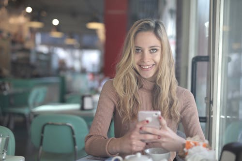 Shallow Focus Photo of Woman Smiling While Holding Smartphone