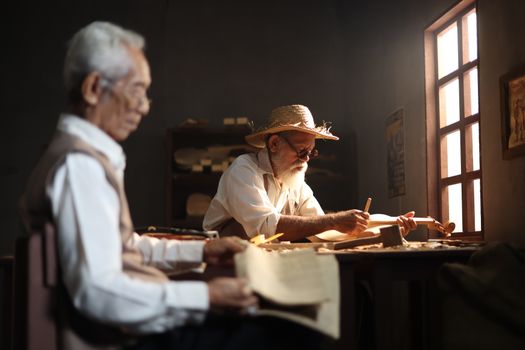 Elderly artisans crafting string instruments in a workshop in Jakarta, Indonesia.