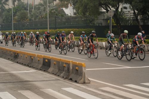Free Cyclists in helmets ride in formation on a city street in Jakarta, Indonesia. Stock Photo