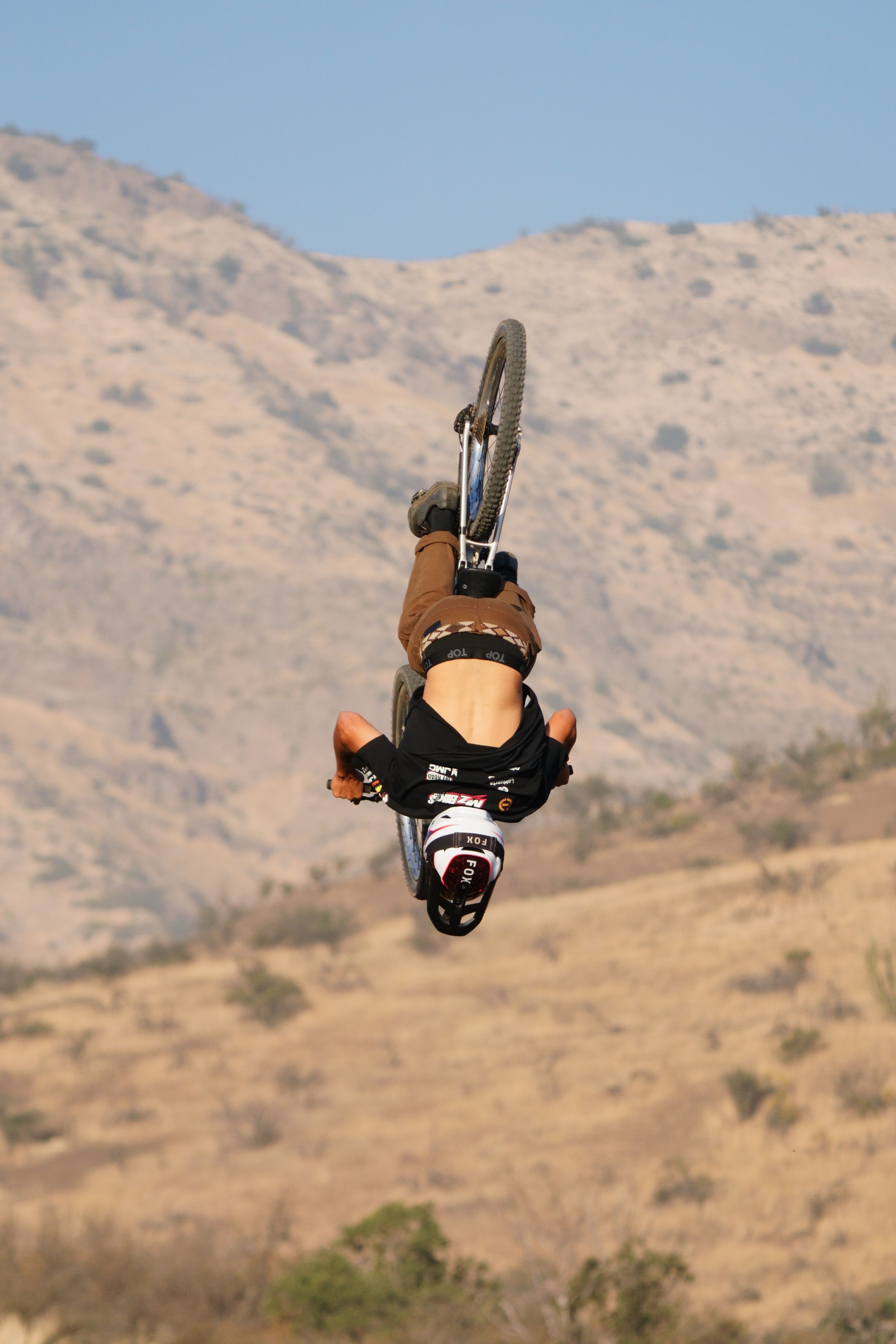 Thrilling mountain biking stunt with a backward flip in a desert setting.
