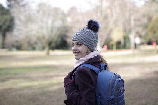 秋天，一位戴着针织帽、背着背包的快乐女人在公园里微笑