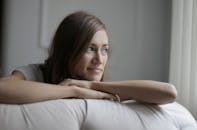 一位年轻女子躺在里面的沙发上，轻轻微笑着看着窗外