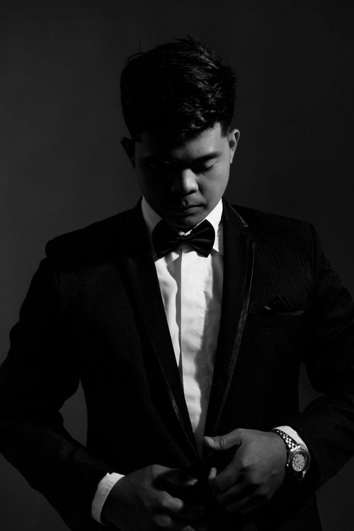 Free A stylish man in a suit adjusts his jacket in a dramatic black and white portrait. Stock Photo
