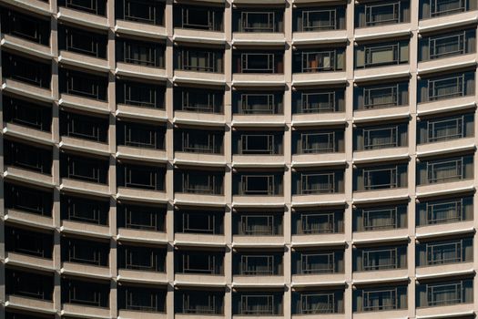 Urban high-rise building with curved facade featuring rows of balconies creating a repetitive pattern.