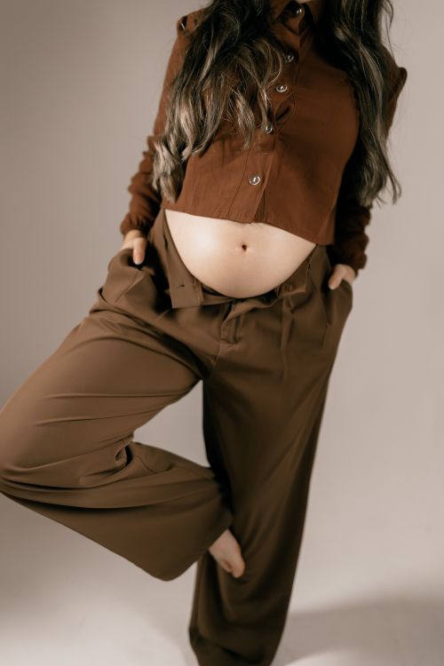 Free Stylish pregnant woman in brown attire posing indoors for a maternity photoshoot. Stock Photo