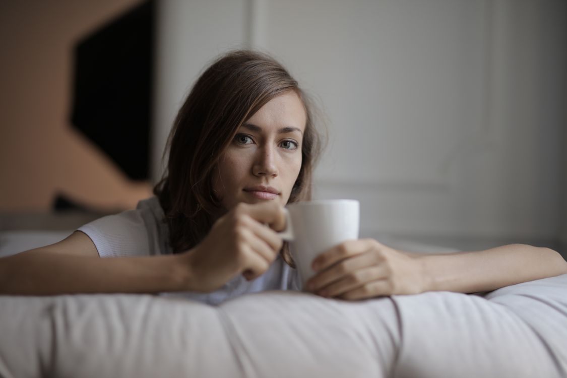 A woman holding a mug while leaning on a sofa in a calm indoor moment