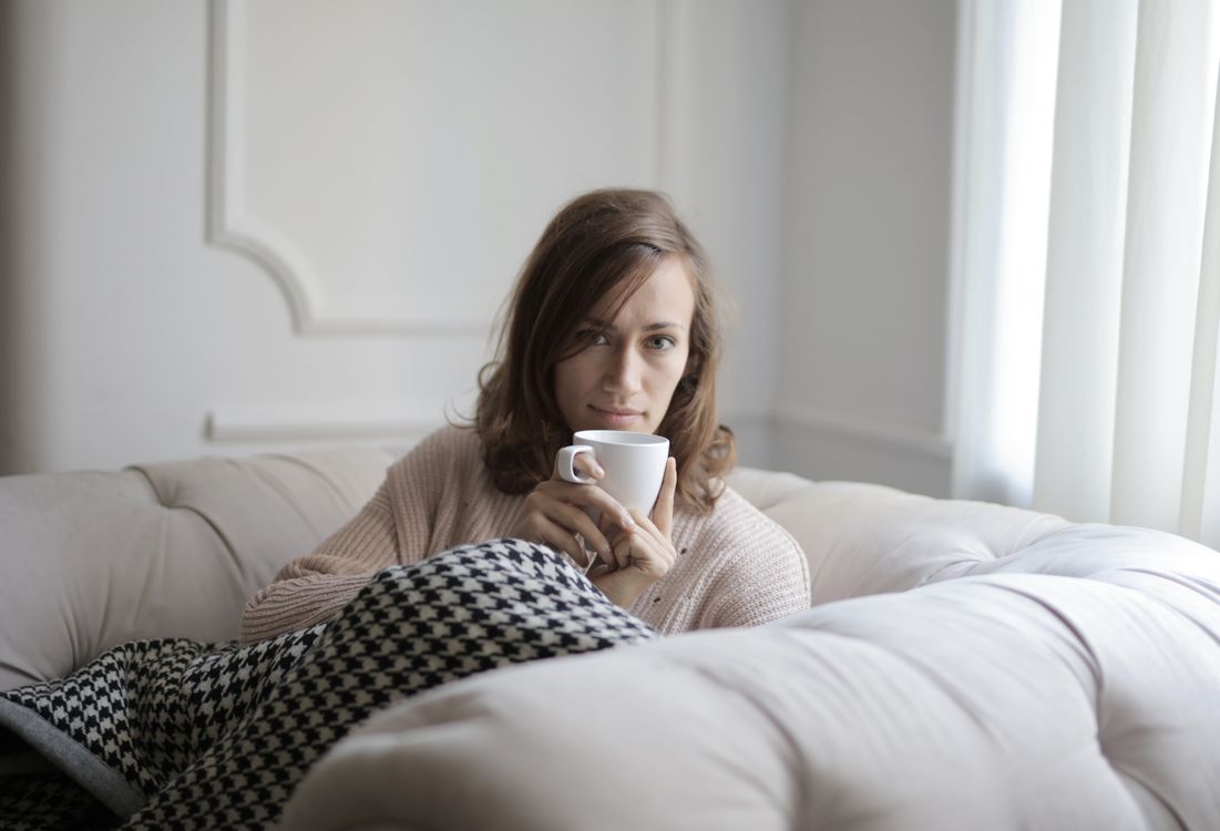 A woman wrapped in a blanket holding a coffee cup in a tranquil moment