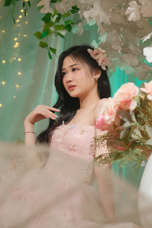 Free Charming portrait of a woman in a pink dress surrounded by floral decor, exuding elegance. Stock Photo