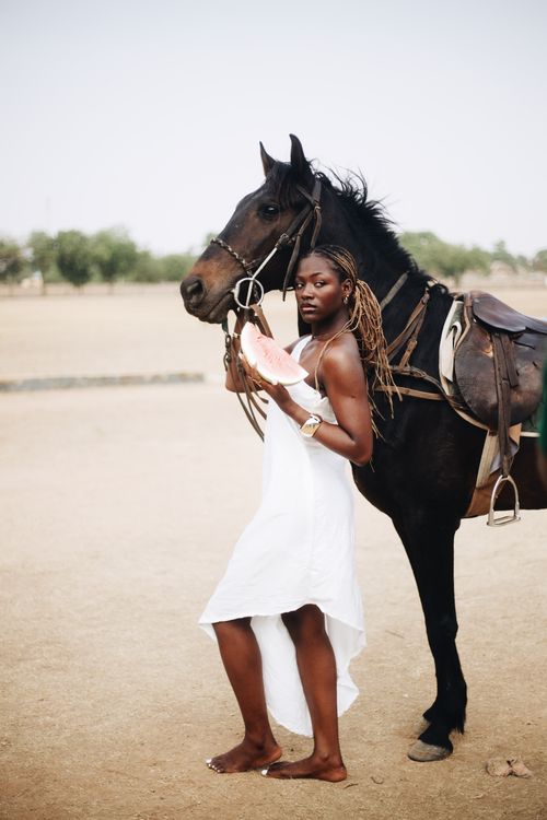 Free Stylish woman in white dress poses with horse on a sunny day outdoors. Stock Photo