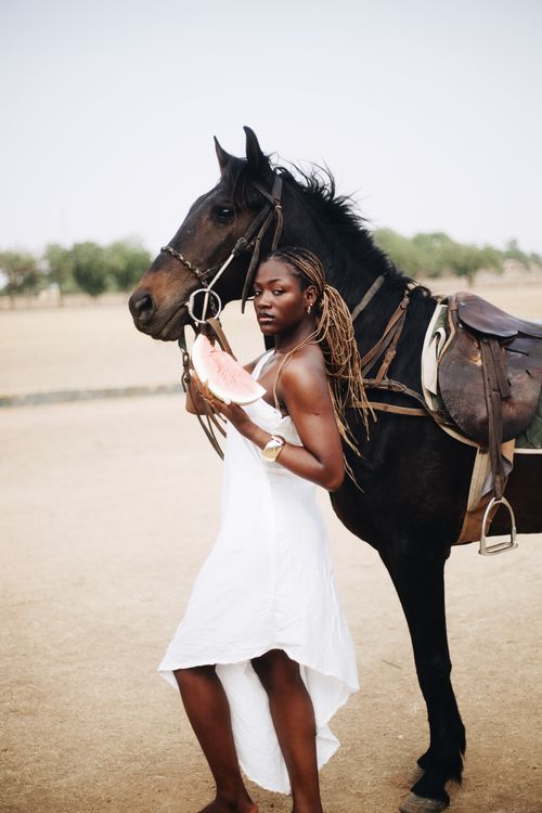 Free Beautiful woman in white dress holding a horse outdoors, showcasing elegance and freedom. Stock Photo