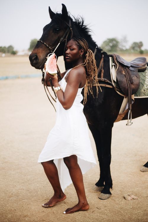 Free Graceful woman in white dress posing with a horse in an outdoor setting. Stock Photo