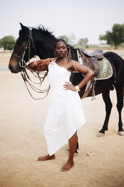 Free A stylish woman in a white dress poses confidently with a horse outdoors. Stock Photo