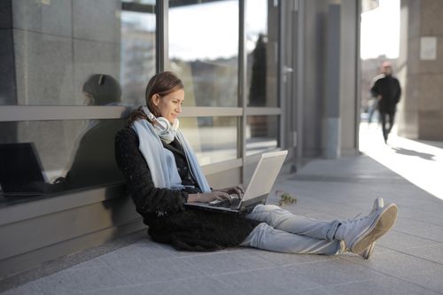 Free Woman using laptop outdoors, enjoying wireless technology and modern lifestyle. Stock Photo