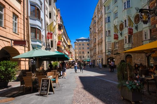 Free Busy street in Innsbruck, Austria, showcasing vibrant facades and outdoor cafes under clear blue skies. Stock Photo