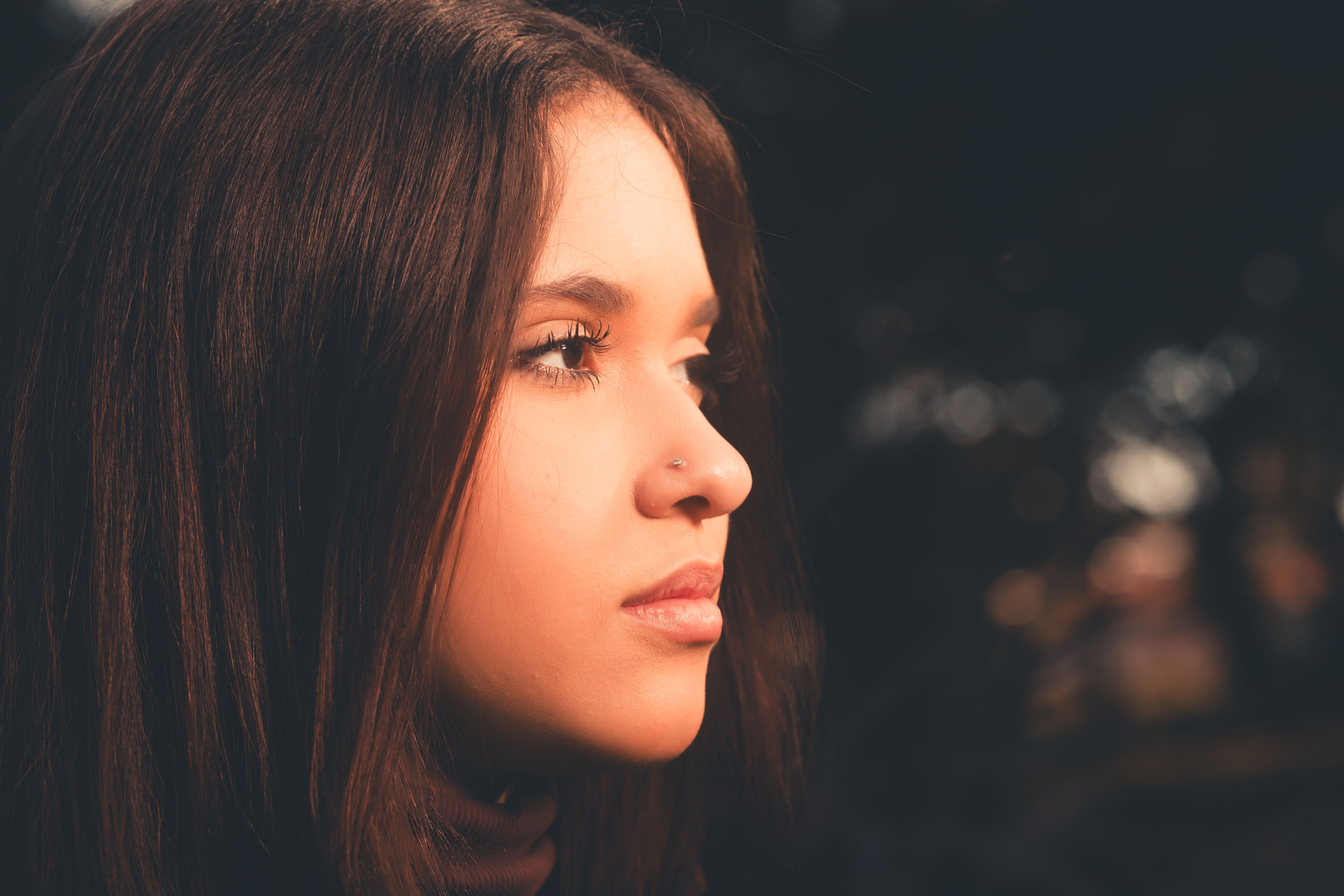 A serene profile portrait of a young woman with soft lighting and blurred background.
