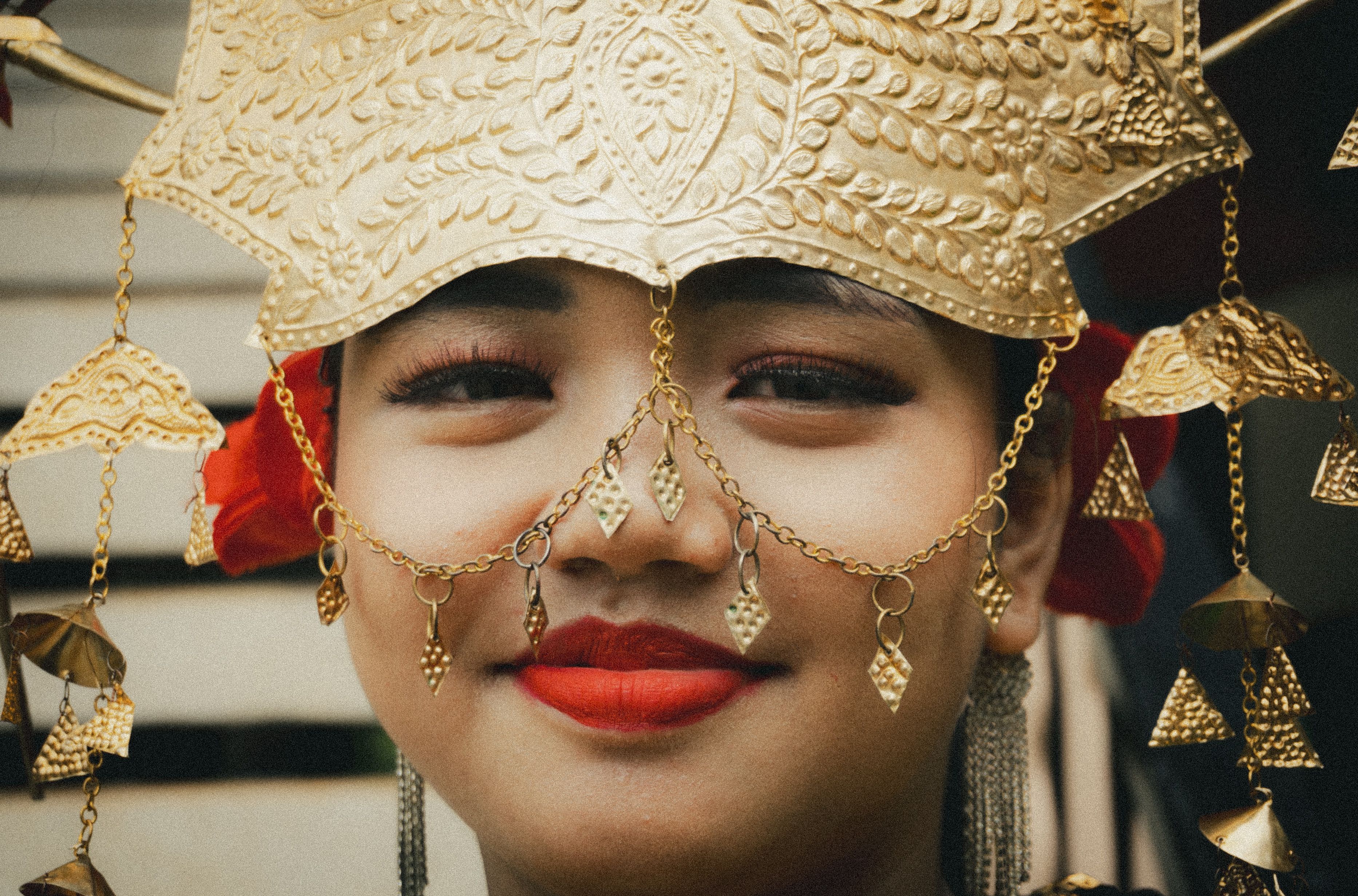 Close-up of a smiling Batak woman wearing a traditional golden headdress.