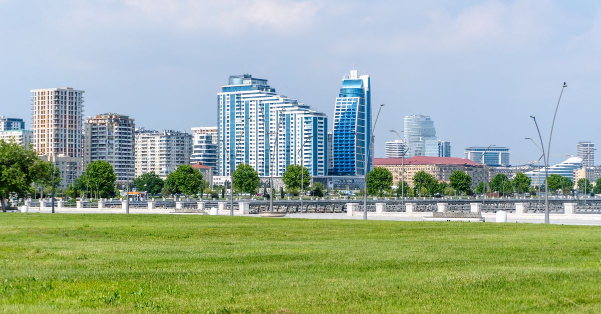 Skyline of Baku, Azerbaijan featuring modern skyscrapers and a lush green park on a sunny day.
