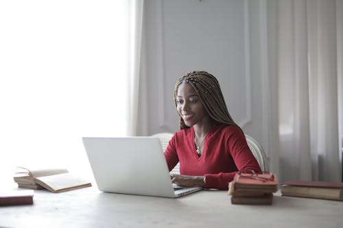 Woman in Red Long Sleeve Shirt Using Macbook Air