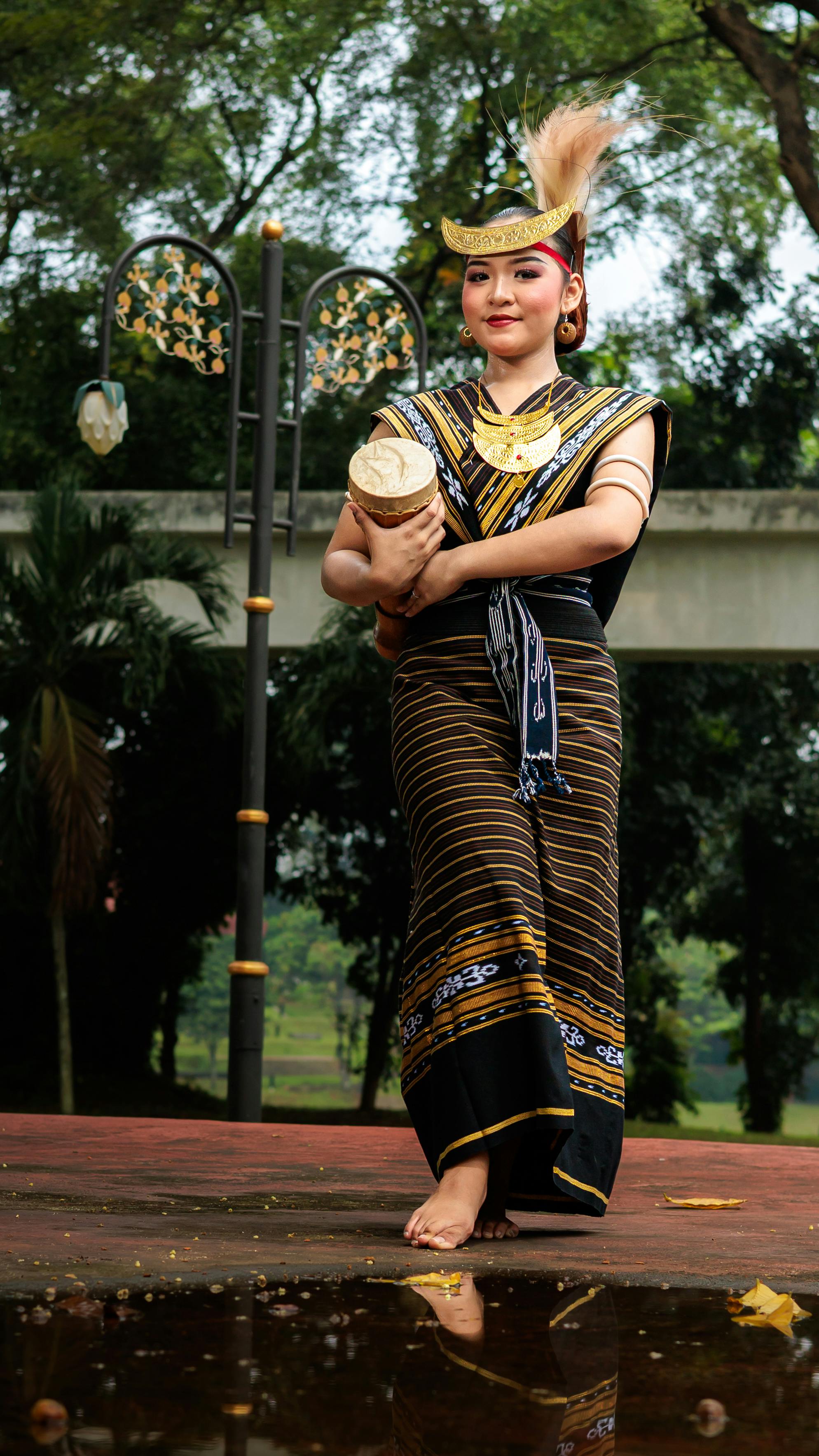 A woman in traditional attire performs a cultural dance outdoors.