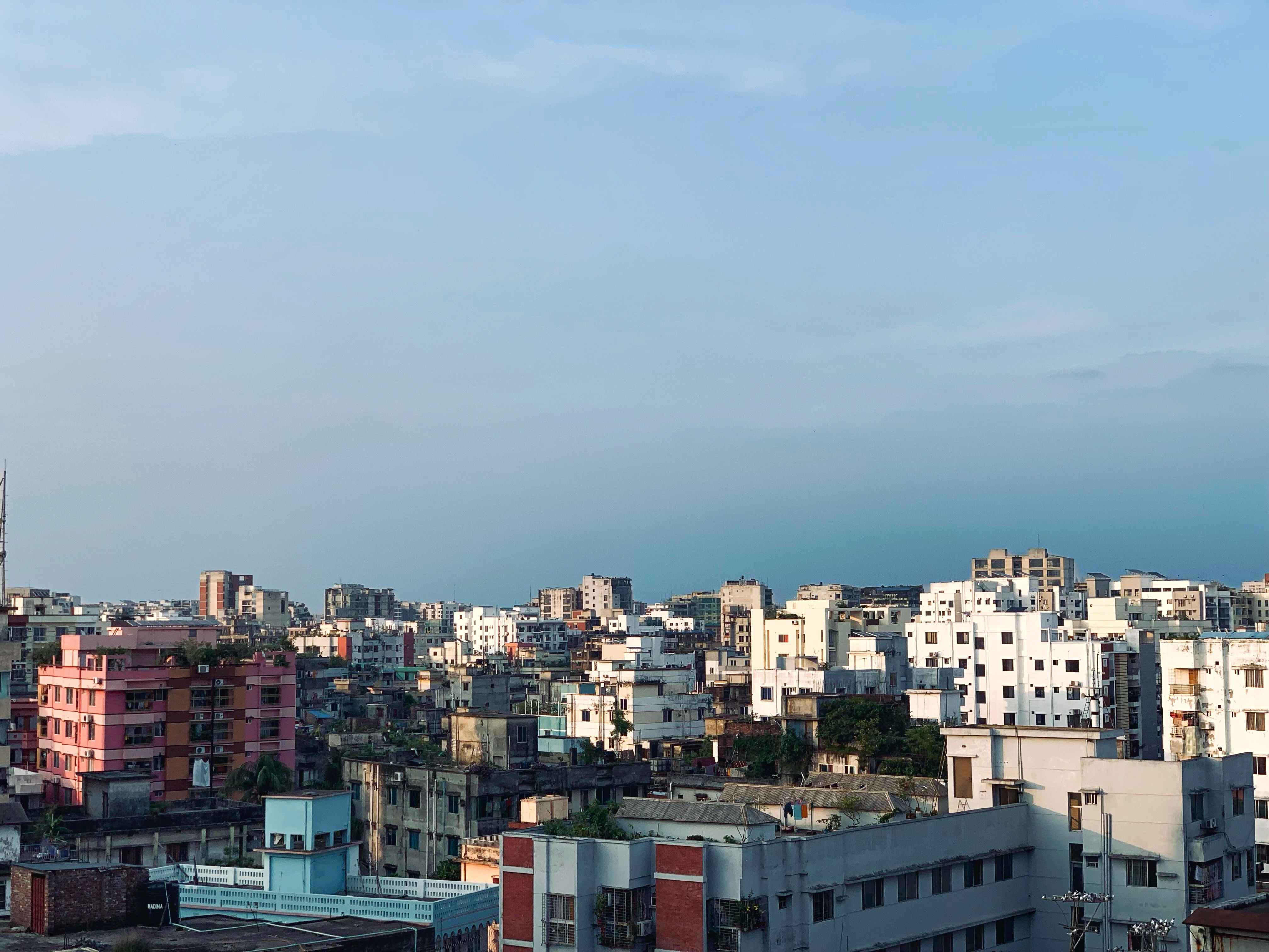 Aerial cityscape of Dhaka, Bangladesh with diverse architecture and clear blue sky.