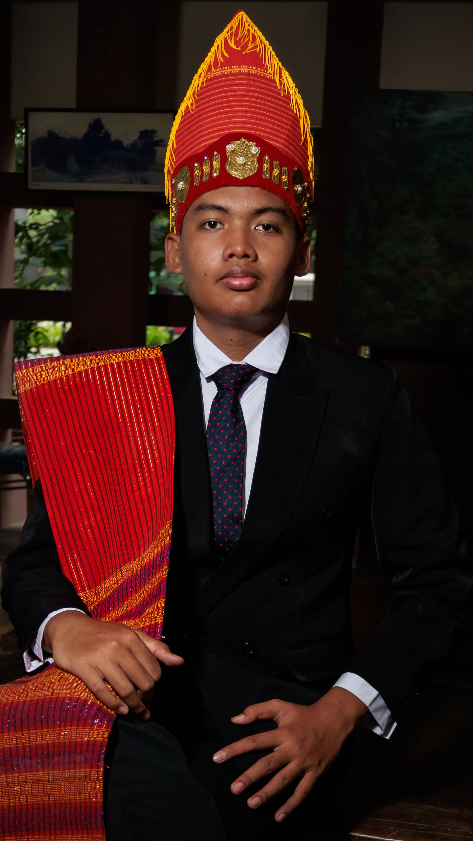 Portrait of a young man wearing traditional Indonesian attire indoors, conveying cultural pride.