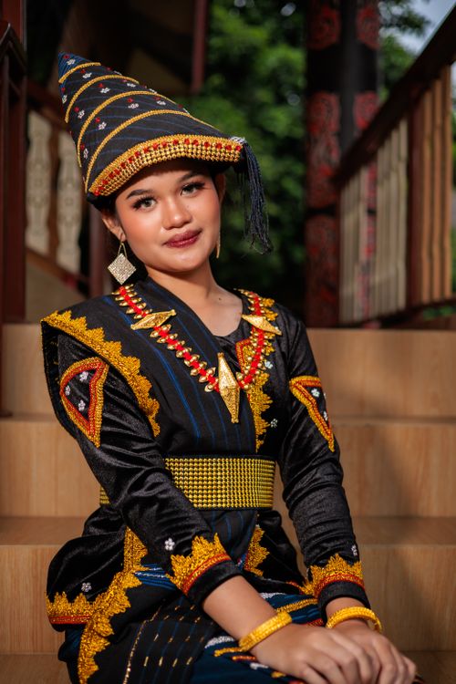 Gratuit Une femme vêtue d'une tenue traditionnelle indonésienne aux couleurs chatoyantes pose sur un escalier à Jakarta. Photos
