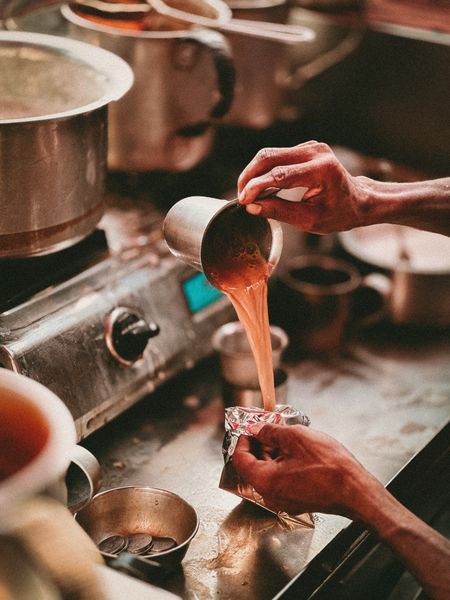 Chai being strained into a cup, the hot-steeped method for Moody Teas chai blends