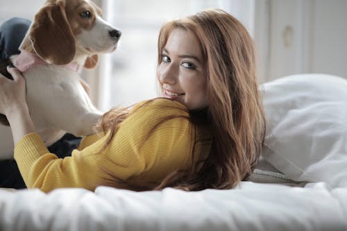 Wanita Dengan Sweater Kuning Memeluk Anjing Pendek Putih Dan Coklat