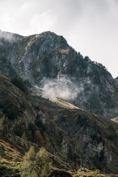 A mist-covered mountain in the Pyrenees with lush vegetation and cliffs.