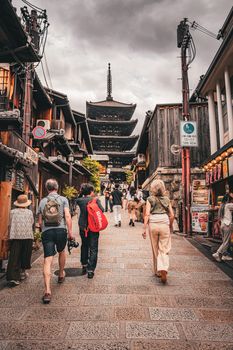 Tourists stroll down a historic street towards the iconic Yasaka Pagoda in Kyoto, Japan, showcasing traditional architecture.