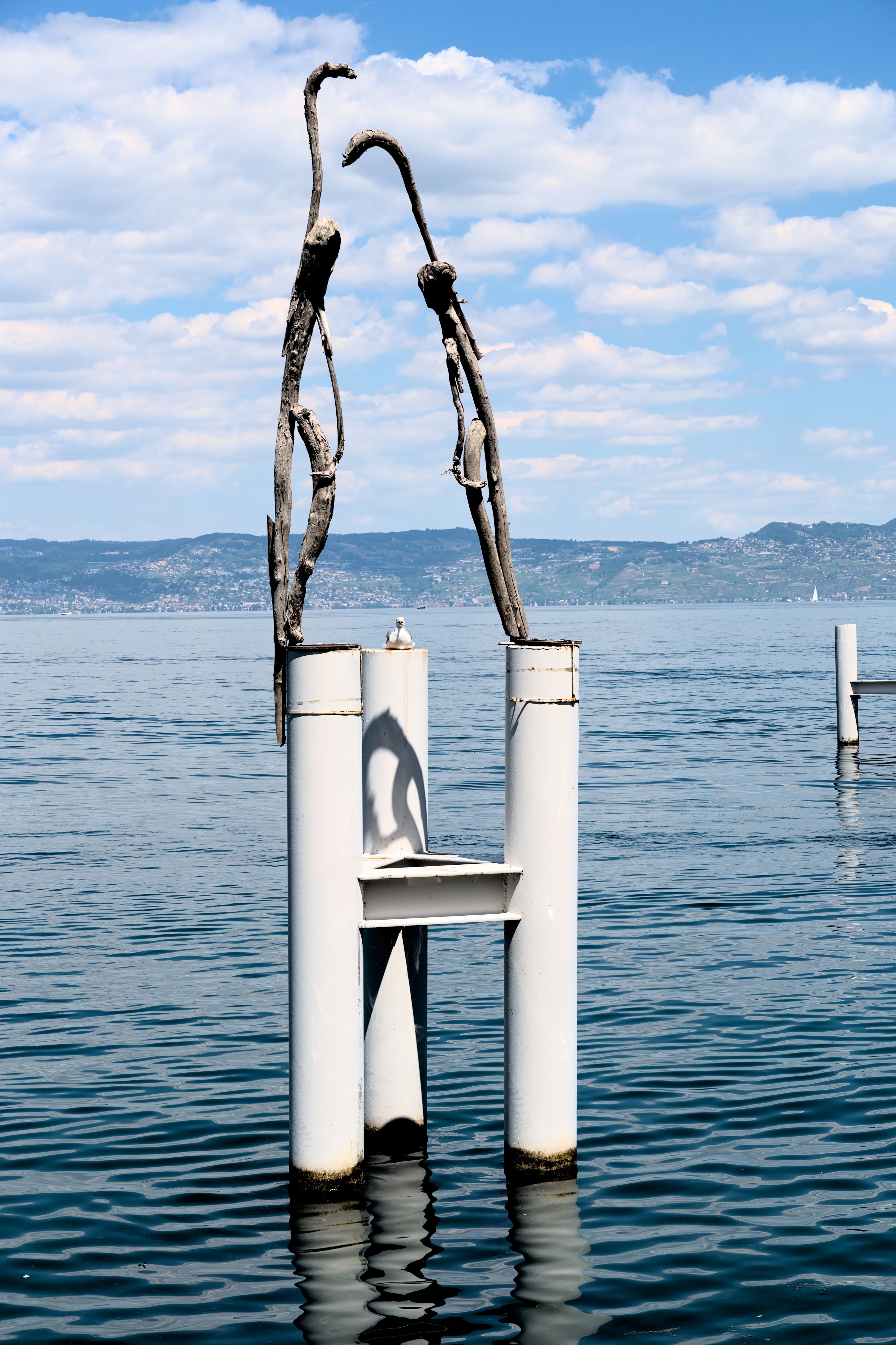 Sculpture emerging from Lake Geneva with picturesque mountains in the background in Evian, France.
