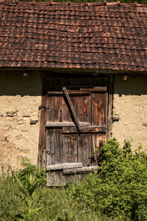 Free A weathered wooden door on a rustic barn in Sakarya, Türkiye, surrounded by lush greenery. Stock Photo