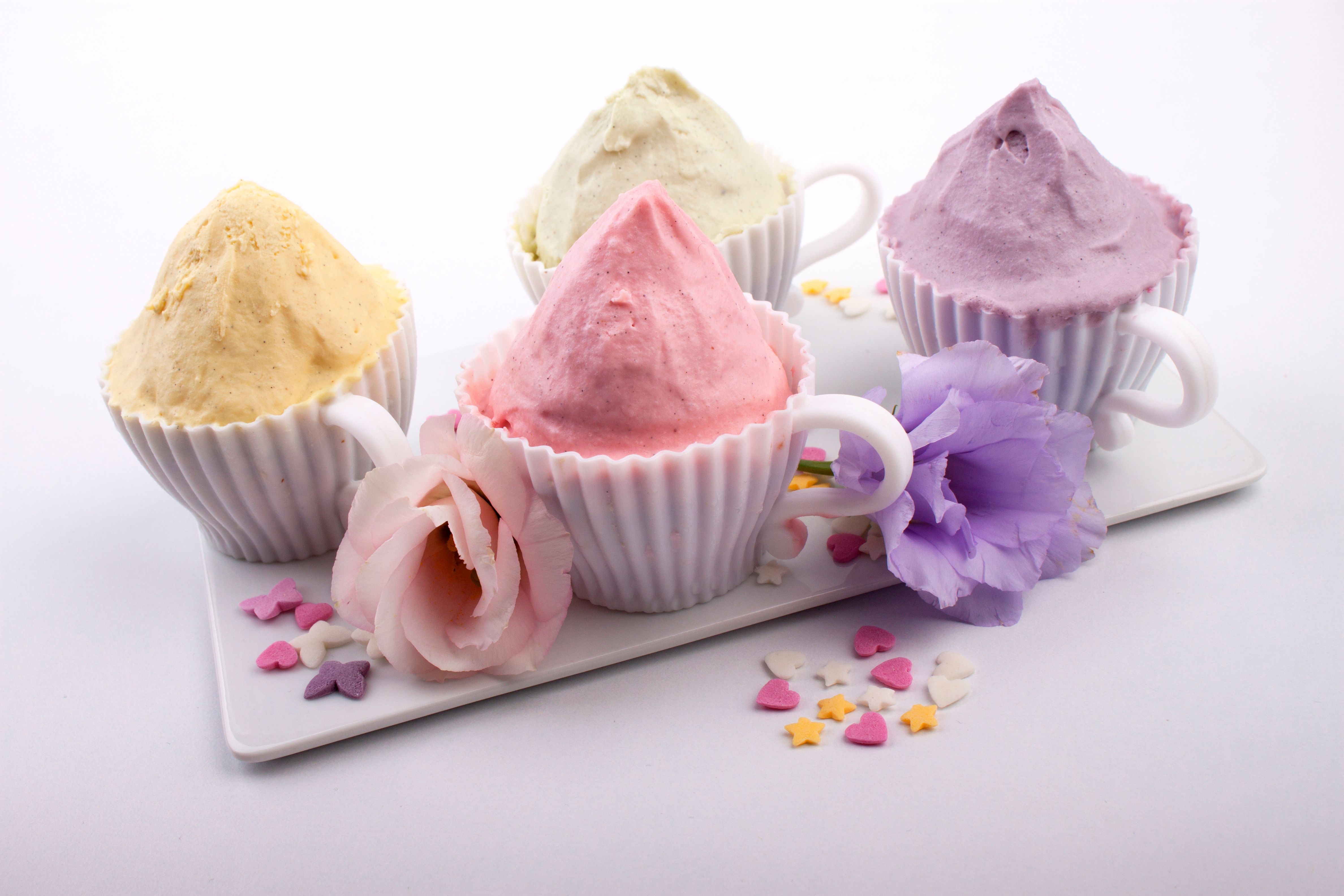 Rounded scoops of colorful gelato in dainty floral cups, a soft and charming pastel dessert setting