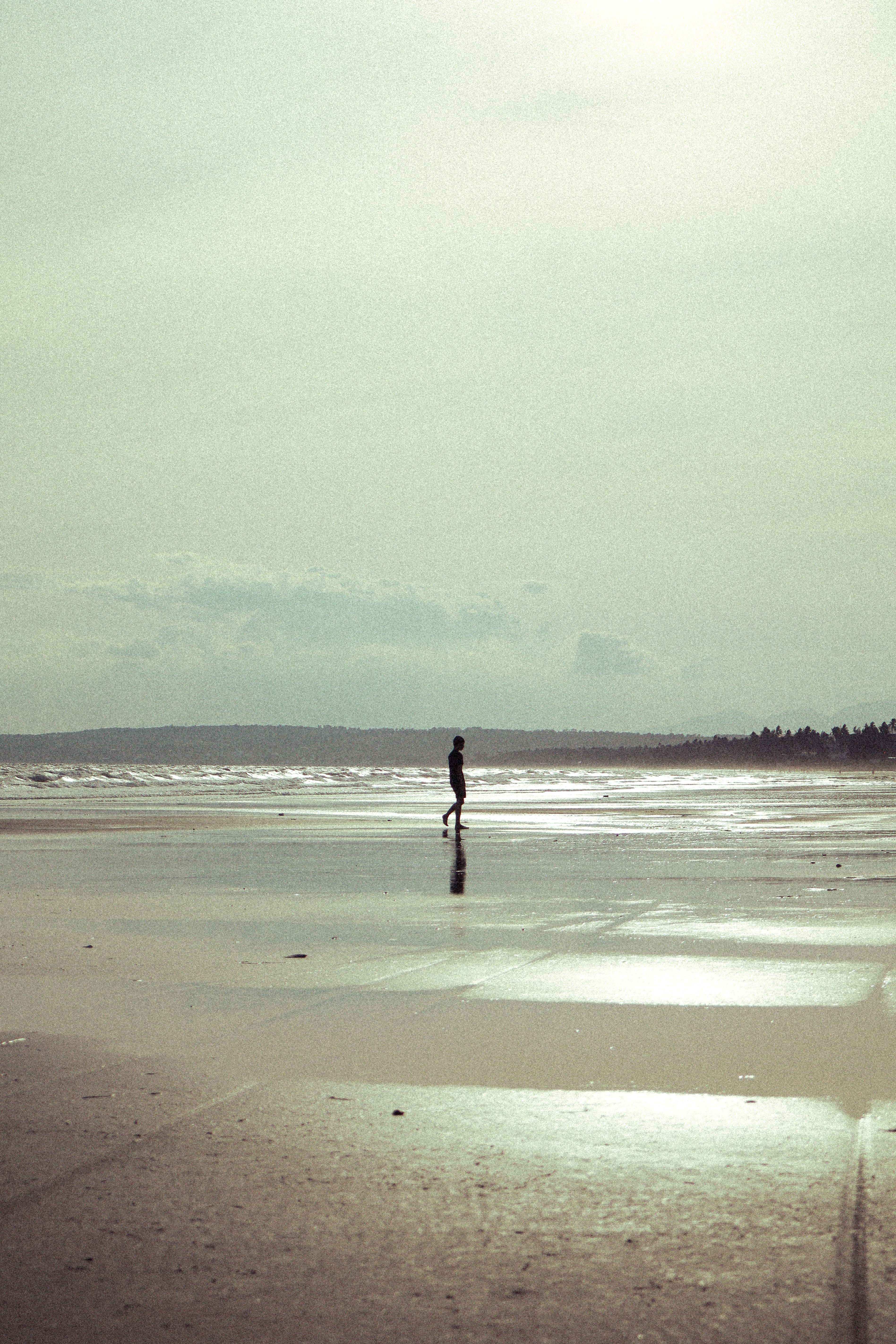 A solitary person strolls along a serene beach in Vietnam, under an overcast sky. Perfect for travel and relaxation themes.